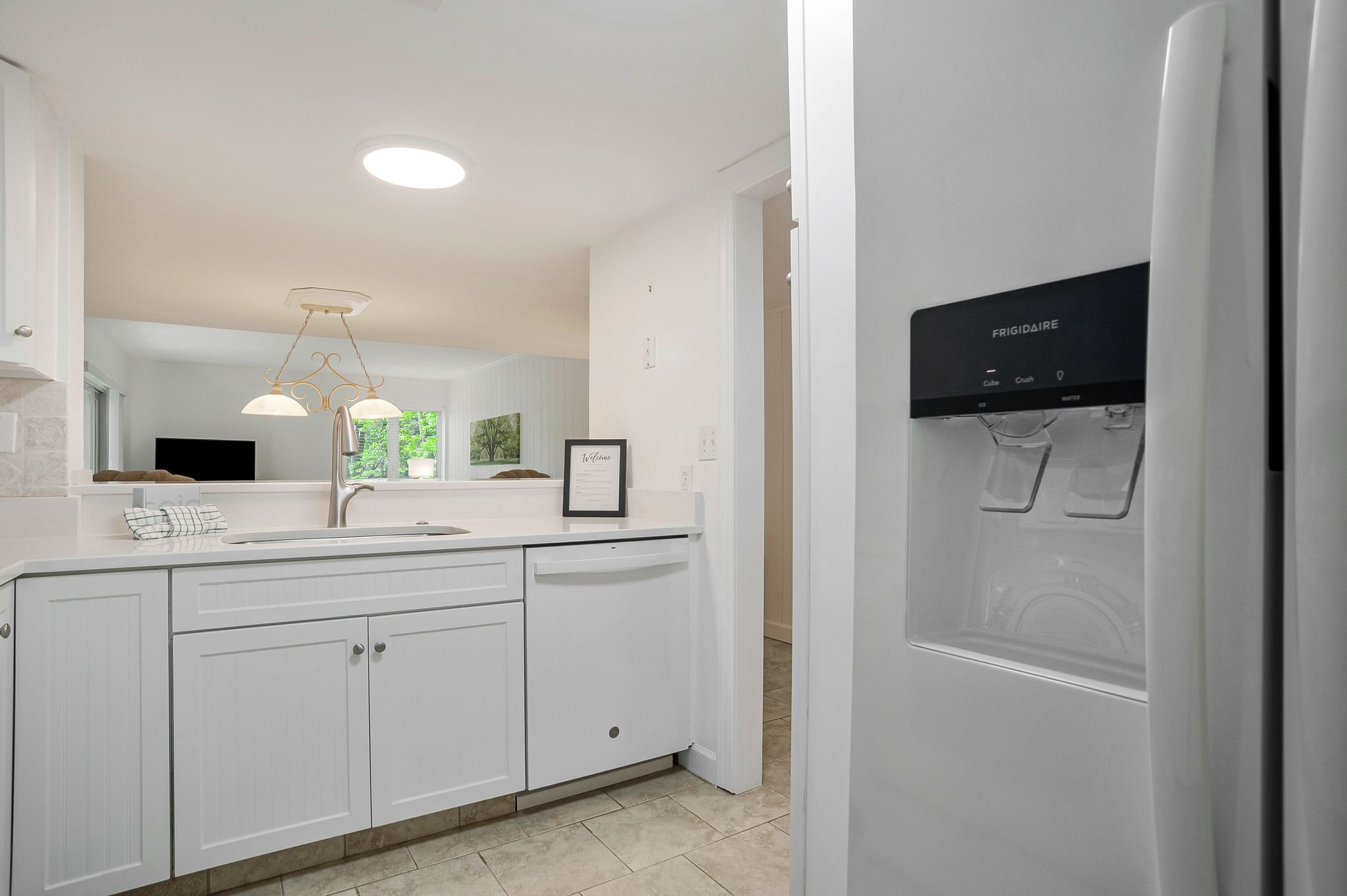 A modern kitchen with white cabinetry, a built-in dishwasher, and a water dispenser.