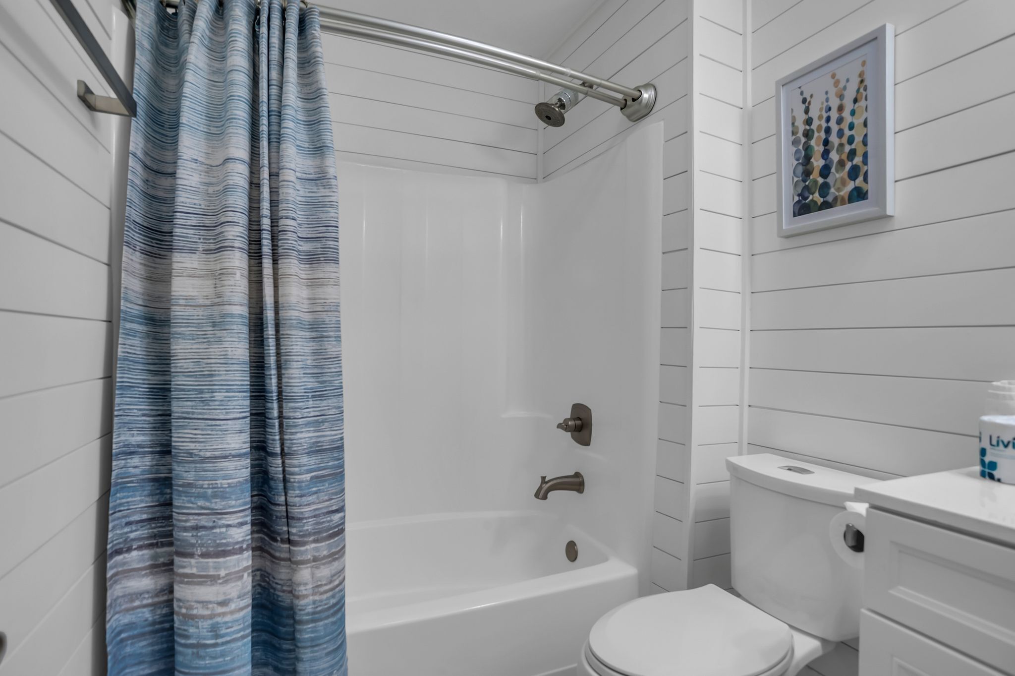 A bathroom with a bathtub, toilet, and a shower curtain.