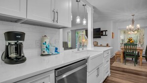 A modern kitchen with white cabinets, a coffee maker, and a dishwasher.