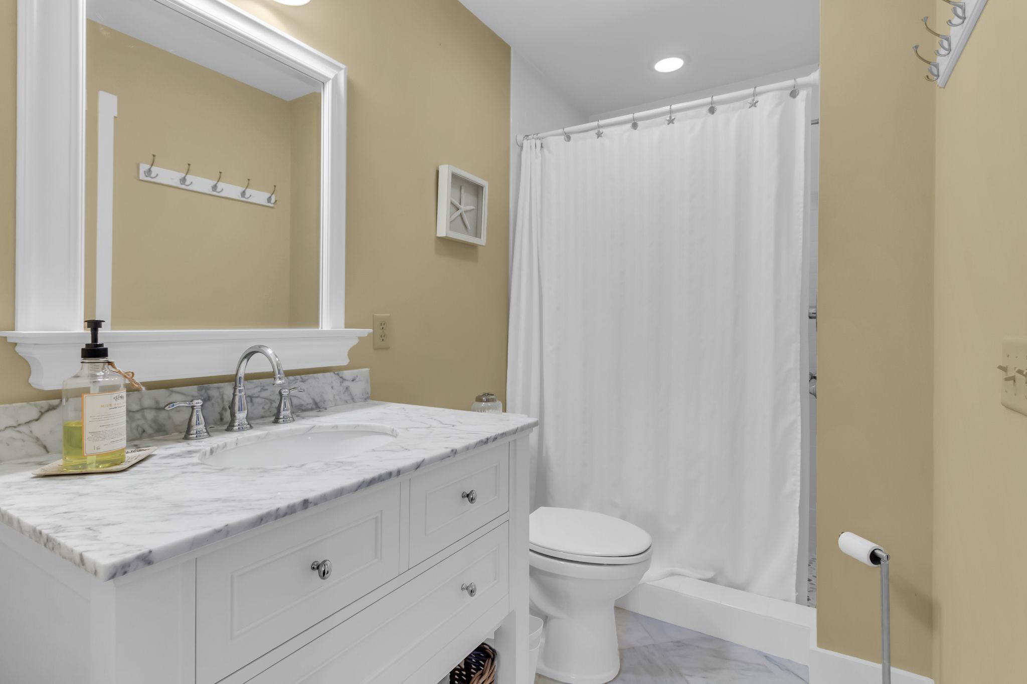 Une salle de bain avec un lavabo blanc, un miroir et des toilettes.