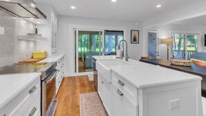 A modern kitchen with white cabinetry, a stainless steel range hood, and a wooden countertop. - 26 Muirfield Road at The Sea Pines Resort (Hilton Head Island)