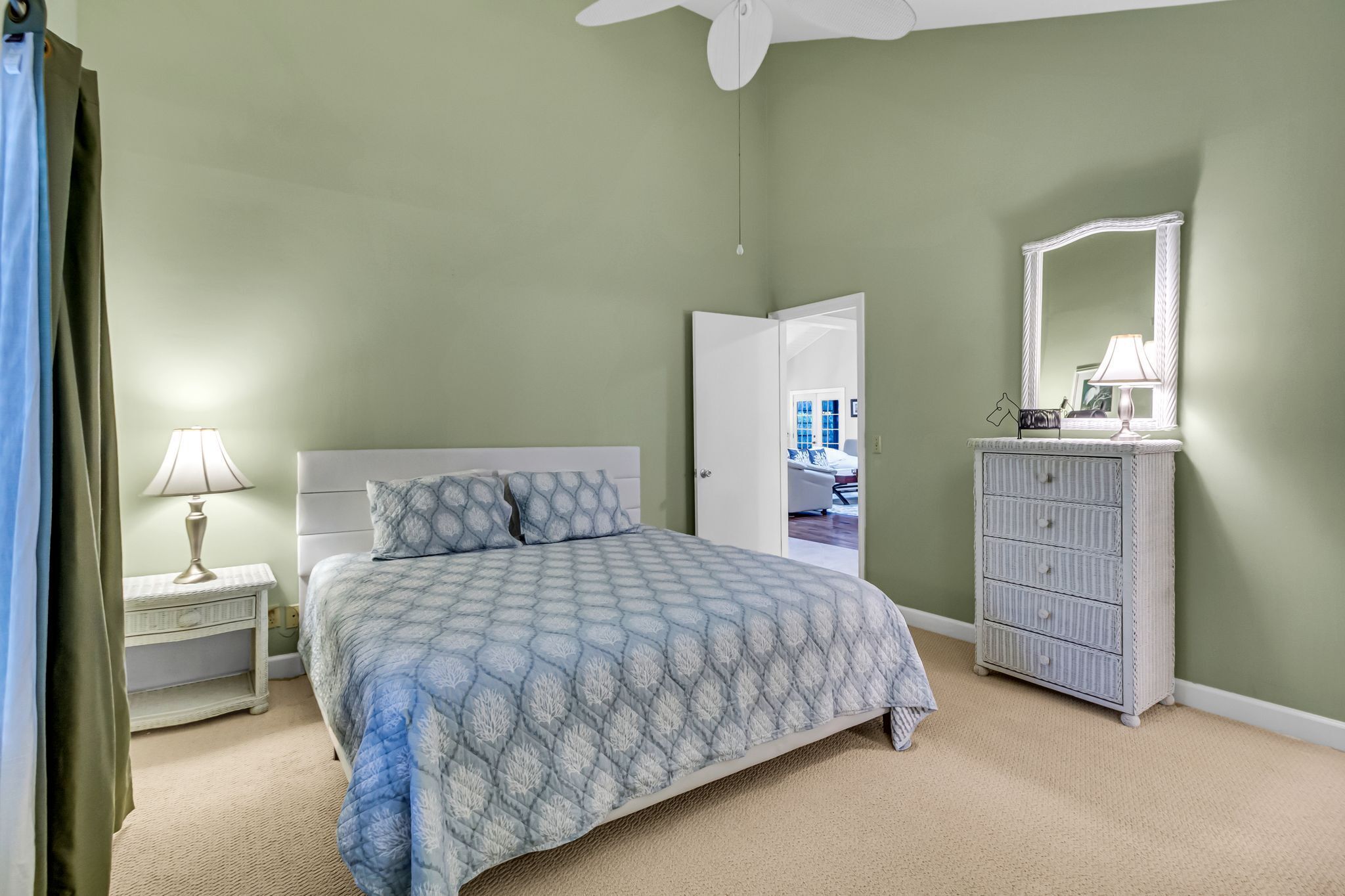 A bedroom with a bed, nightstand, dresser, and a mirror.
