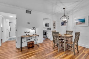 A dining area with a wooden table and chairs, a pendant light, and framed pictures on the wall. - 1025 Caravel Court at The Sea Pines Resort (Hilton Head Island)
