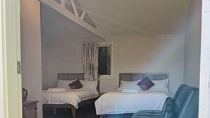 Un dormitorio con dos camas, un sofá azul y una ventana con cortinas.