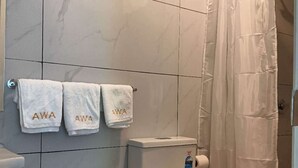 Un baño con inodoro, bote de basura y cortina de ducha.