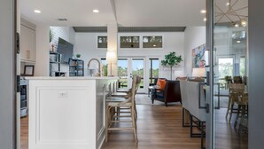 A spacious kitchen with a central island, wooden bar stools, and a dining area with a table and chairs. - 6966 Fairway One at The Sea Pines Resort (Hilton Head Island)