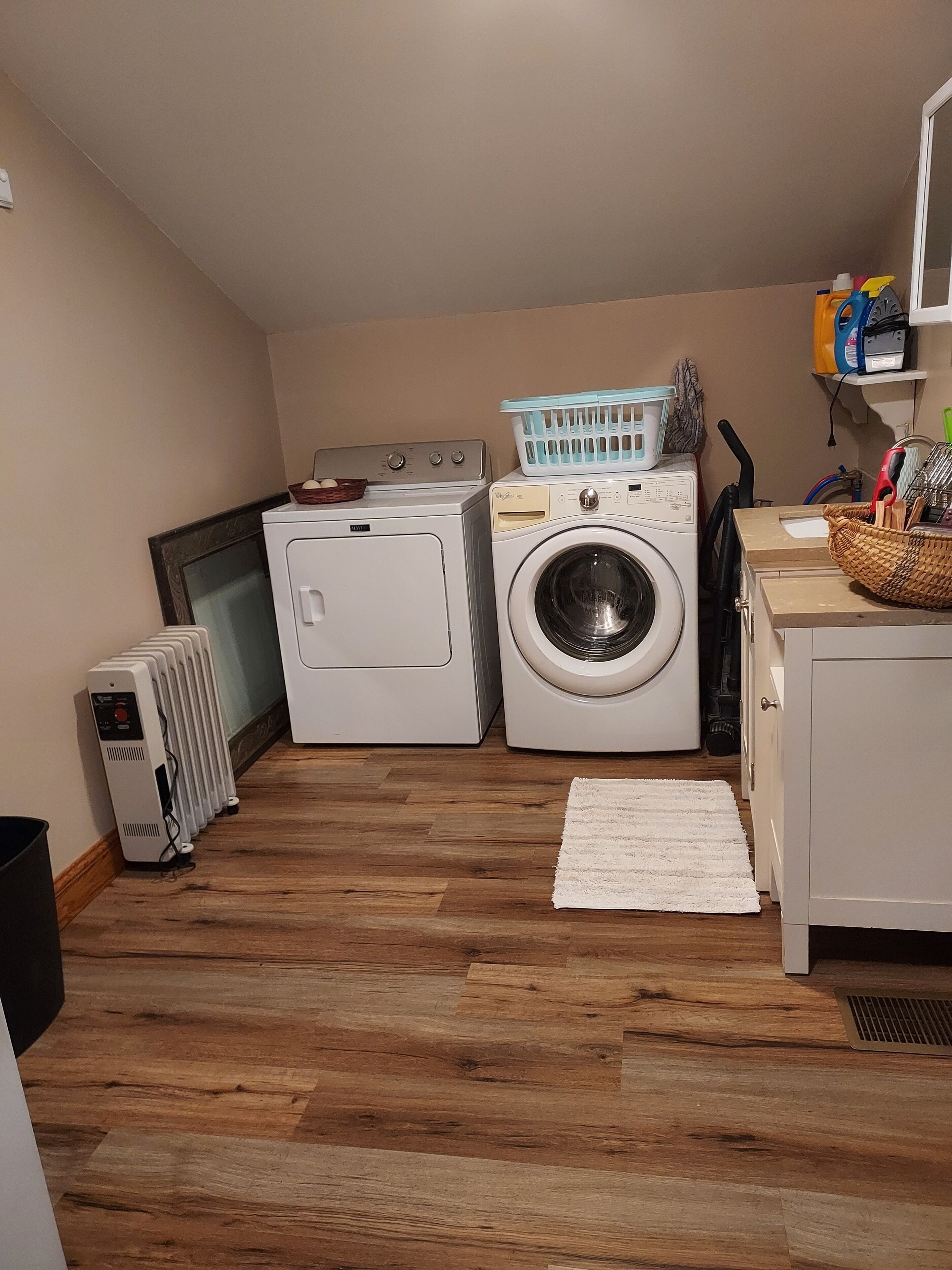 Un cuarto de lavandería con secadora, lavadora y cestas de ropa apiladas.