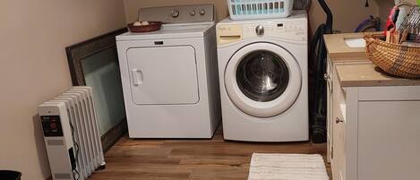 Un cuarto de lavandería con secadora, lavadora y cestas de ropa apiladas.