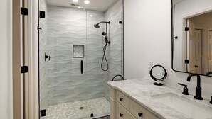 A modern bathroom with a glass-enclosed shower, a marble sink, and a large mirror. - 97 Fairway Lane at The Sea Pines Resort (Hilton Head Island)