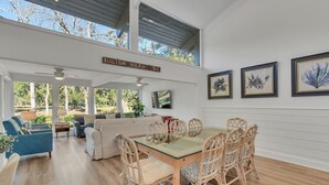 A spacious living area with a glass-top dining table surrounded by wicker chairs, a sofa, and a coffee table. - 97 Fairway Lane at The Sea Pines Resort (Hilton Head Island)