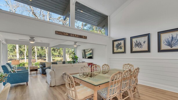 A spacious living area with a glass-top dining table surrounded by wicker chairs, a sofa, and a coffee table. - 97 Fairway Lane at The Sea Pines Resort (Hilton Head Island)