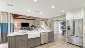 A modern kitchen with a large island, stainless steel appliances, and a herringbone wood floor.