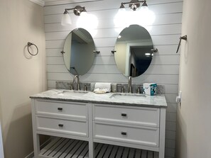 A bathroom with a double vanity, two round mirrors, a marble countertop, and a towel rack. - 1797 Bluff Villas at The Sea Pines Resort (Hilton Head Island)