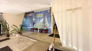 Un hall d’entrée au design moderne, agrémenté d’une grande fresque murale abstraite, d’un comptoir d’accueil et d’un escalier.