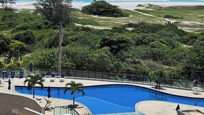 Un resort con piscina, vistas a la playa y exuberante vegetación.