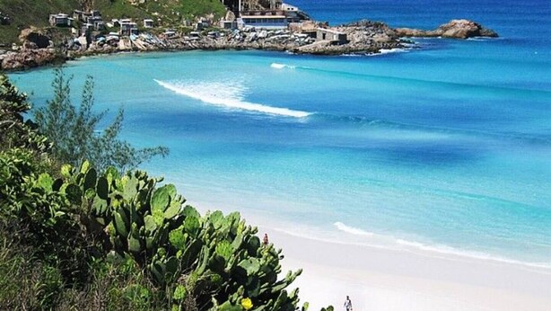 Un resort costero con playa, aguas azules cristalinas y vegetación.
