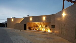 Un edificio moderno con techo plano, un llamativo elemento mural iluminado y un área de entrada pavimentada.