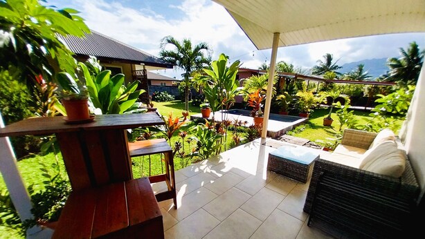 A covered patio with a wooden table and chairs, a small pool, and lush greenery. - Tahiti - Bungalow Toah Toru (Taiarapu-Ouest)