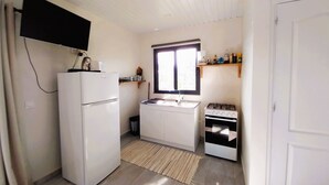 A compact kitchen with a refrigerator, sink, stove, and a window. - Tahiti - Bungalow Toah Toru (Taiarapu-Ouest)