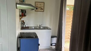 Una cucina compatta con fornello, lavello e un piccolo frigorifero.