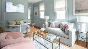 Una sala de estar con sofá, sillón, mesa de centro y una mesita de noche con lámpara.