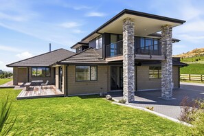 A modern two-story house with a stone facade, large windows, and a covered patio area. - Tranquil and Unique In A Gated Grandview Estate Community With Amazing Views (Taupō)