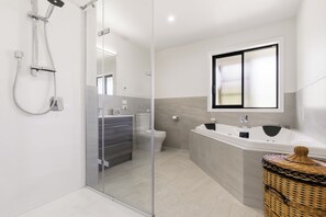 A modern bathroom with a glass shower enclosure, a toilet, and a bathtub. - Tranquil and Unique In A Gated Grandview Estate Community With Amazing Views (Taupō)