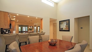 Un comedor amplio con una mesa y sillas de madera, una cocina con electrodomésticos modernos y un gran ventanal que proporciona luz natural.