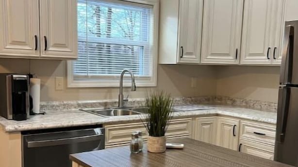 A kitchen with white cabinets, a built-in dishwasher, a sink, and a window with blinds. - Guest house in Hurricane Mills (Hurricane Mills)