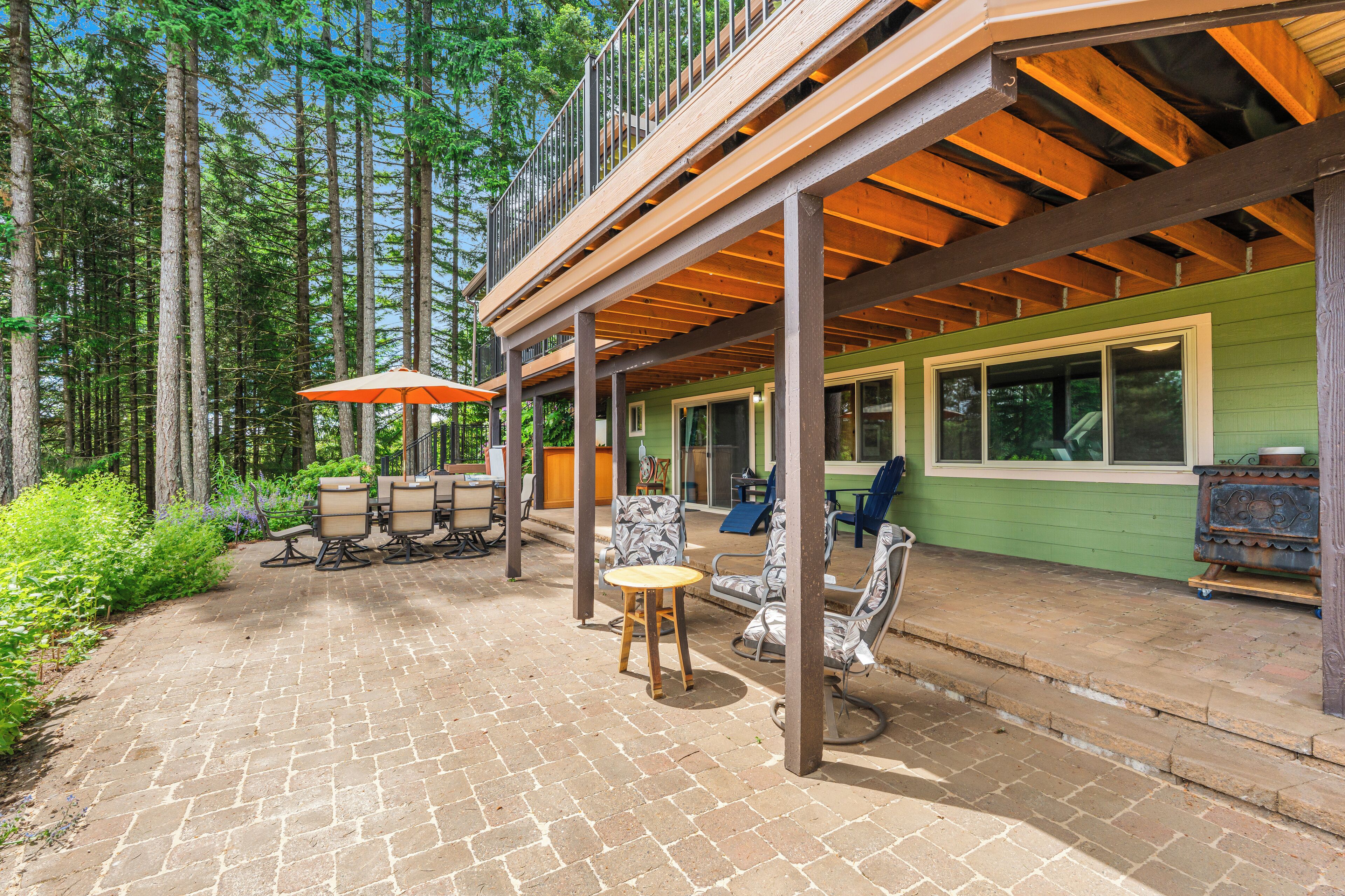 A covered patio with outdoor furniture, a wooden deck, and a view of the surrounding forest.