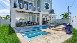 A two-story house with a backyard pool, outdoor seating, and a covered patio area. - 209 Seabreeze Escape: NEW 5BR Pool Home, Close to Beach! (Fort Myers Beach)