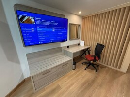 Un espacio de oficina moderno con un televisor de pantalla plana grande montado en la pared que muestra una guía de televisión.