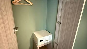 Ein schlichter Raum mit einem Holzschrank, einem kleinen weißen Schrank und einem Holzaufhänger.
