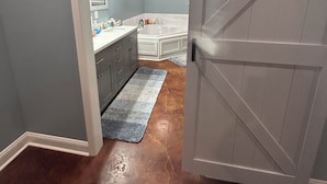 A bathroom with a vanity, sink, mirror, and a bathtub.