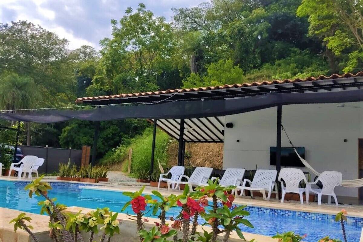 Ein Poolbereich mit überdachter Sitzgelegenheit, weißen Liegestühlen und einem gefliesten Pool.
