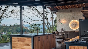 Eine moderne Küche mit einer großen Kochinsel, Holzschränken und Blick ins Freie.
