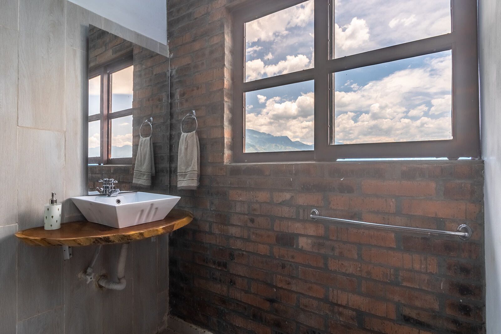 A bathroom with a large window, a sink, and a towel rack.