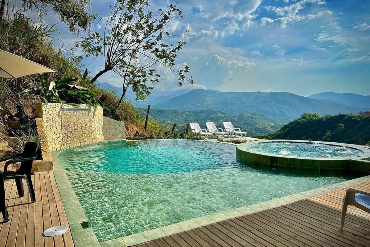 Ein Schwimmbad mit Whirlpool, umgeben von Liegestühlen und einer Holzterrasse.