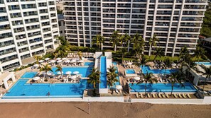 A resort with multiple swimming pools, palm trees, and a beach area. - Gorgeous 1BR with Pools & Sea Views (Puerto Vallarta)