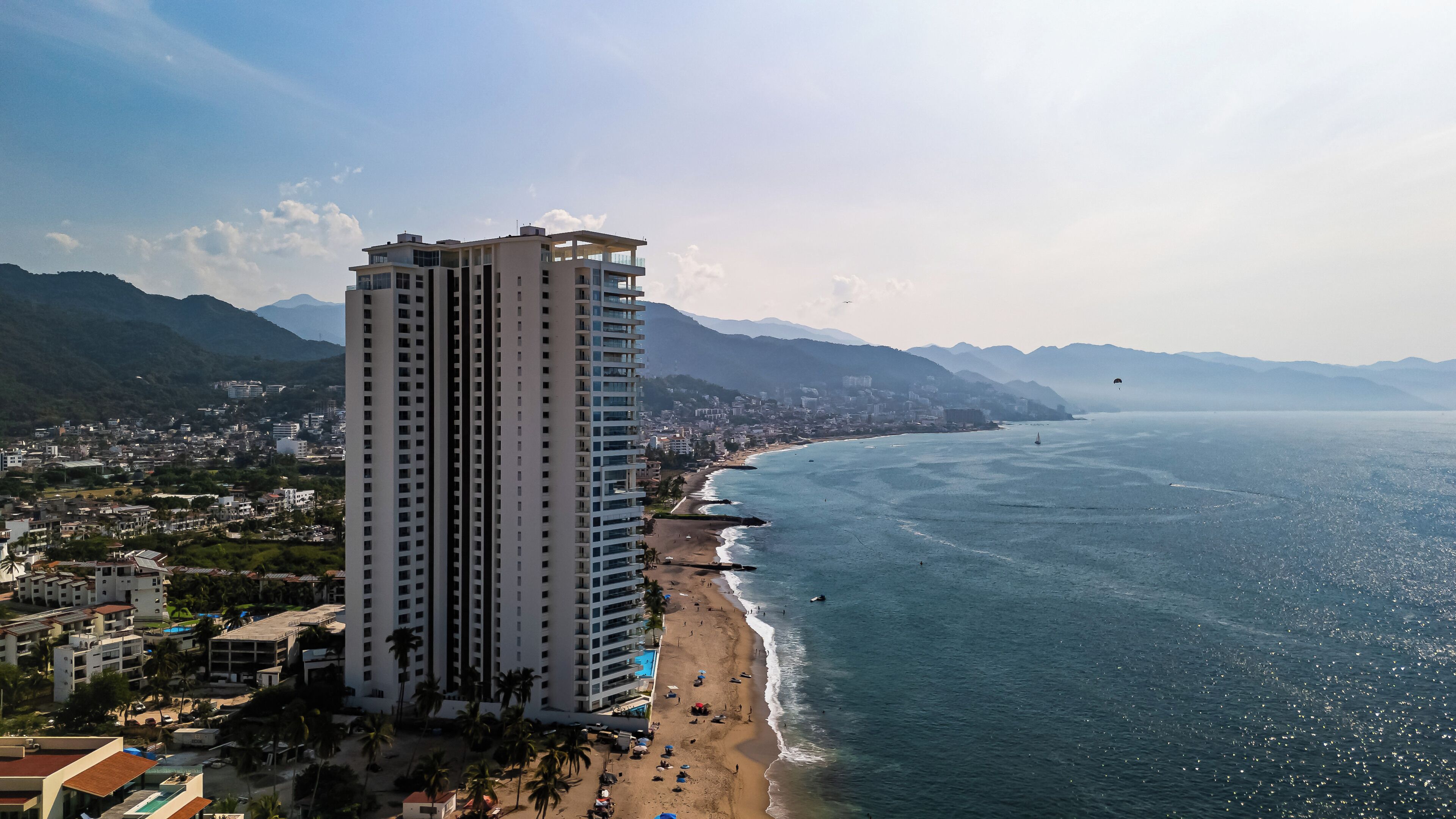 Un grand hôtel avec vue sur la mer, situé près d’une côte bordée de montagnes.