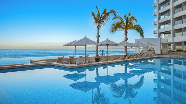 A poolside area with lounge chairs and umbrellas, overlooking a body of water.