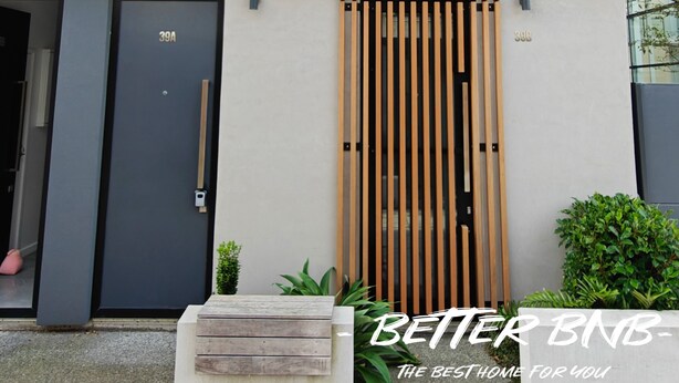 A modern two-story building with a combination of wooden and grey panels, a large window, and a door marked "39A".
