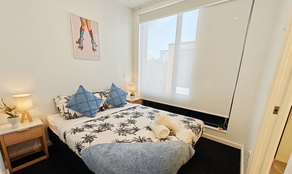 Ein Schlafzimmer mit einem Bett, zwei Nachttischen, einem Fenster und einem Wandbild.