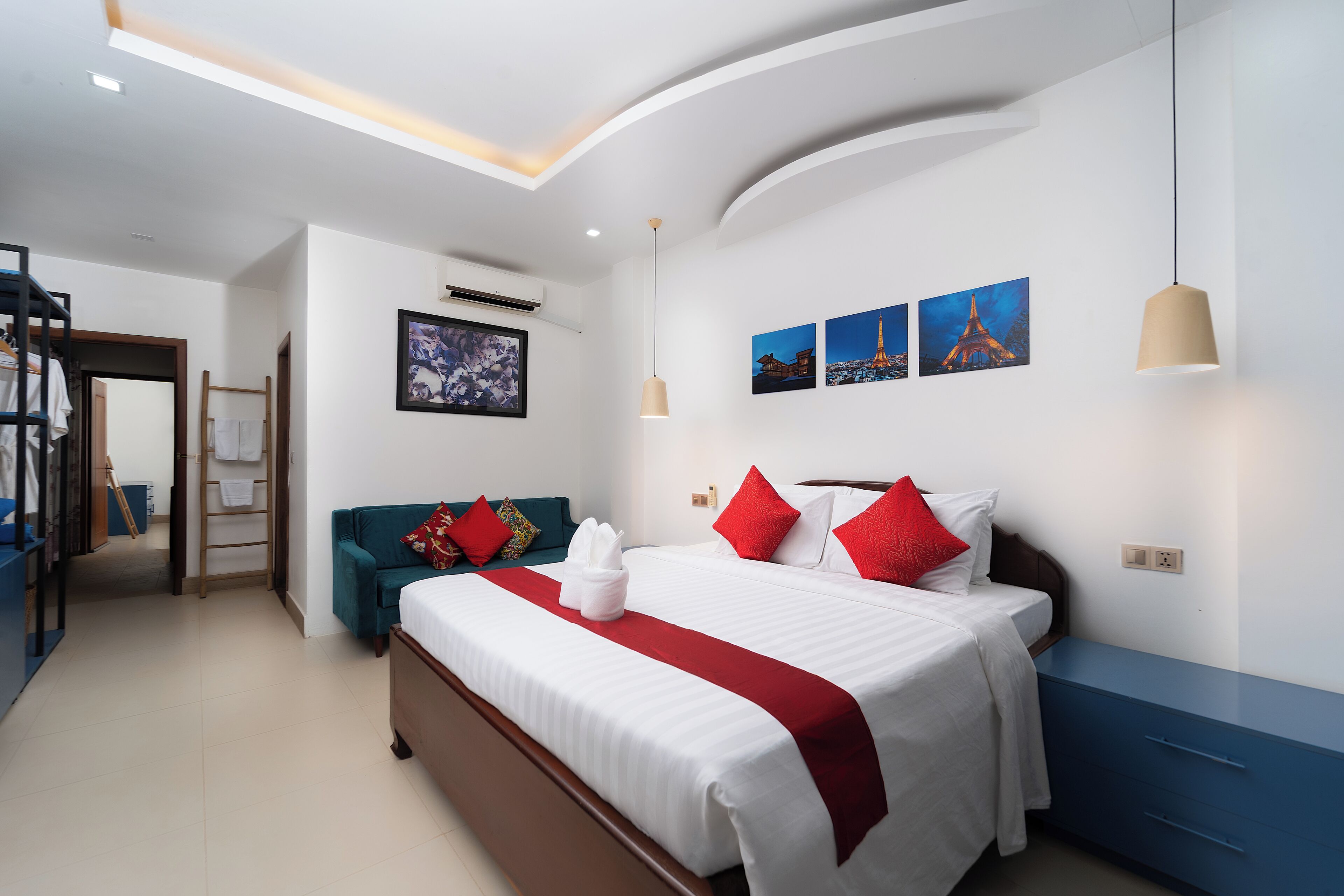 Une chambre d’hôtel comprenant un lit, un canapé, une armoire et un climatiseur fixé au mur.