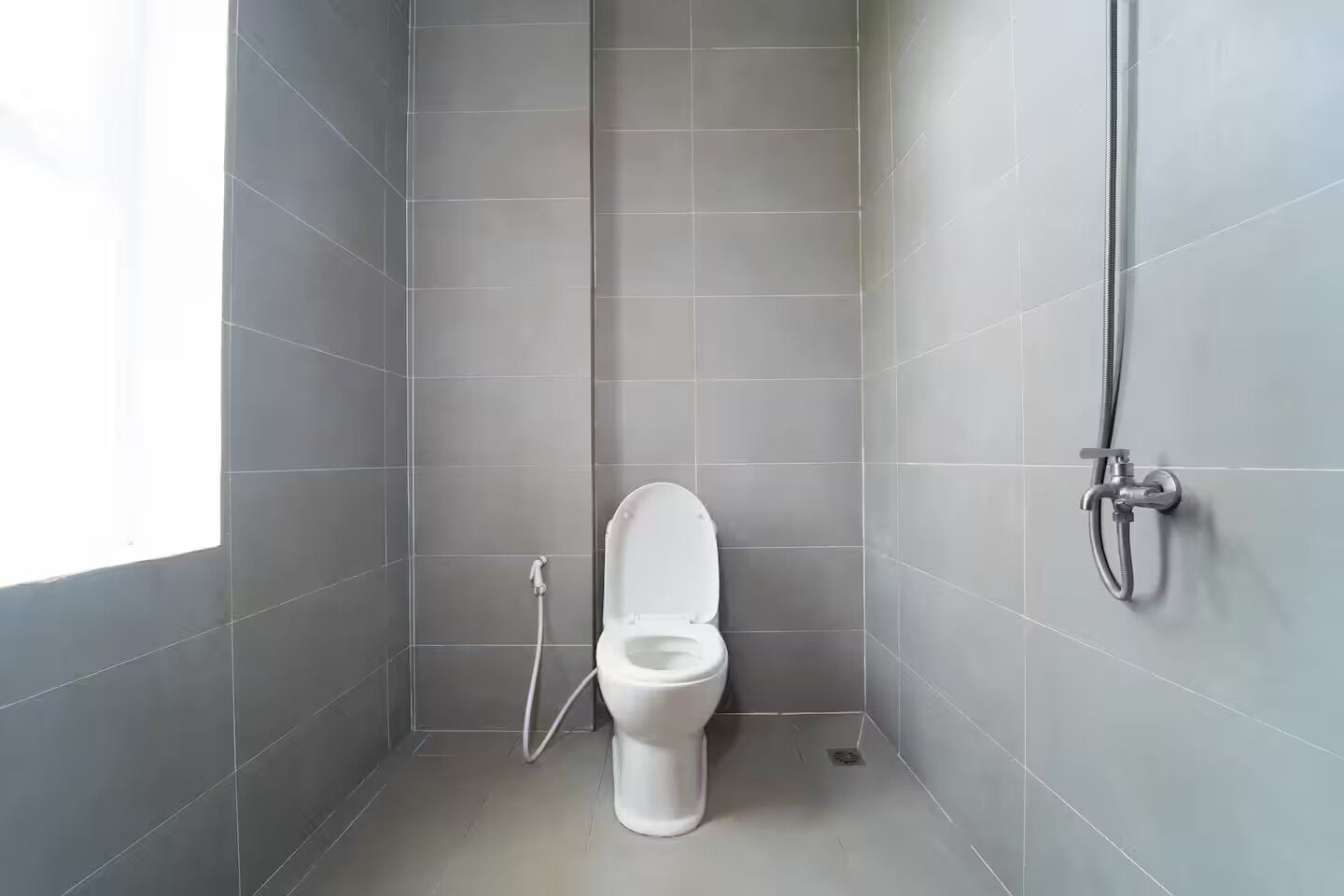 Een compacte, moderne badkamer met toilet, douche en raam.