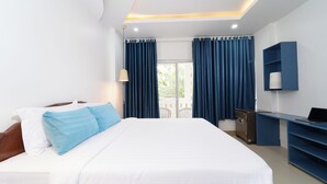 Ein Hotelzimmer mit einem großen Bett, einem Schreibtisch mit Computer und einem Fernseher an der Wand.
