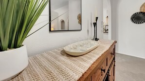 A modern bathroom with a white vanity, a large mirror, a potted plant, and a decorative wall piece.
