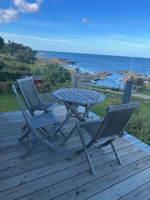 Una terraza de madera con una mesa y dos sillas con vista a un cuerpo de agua.