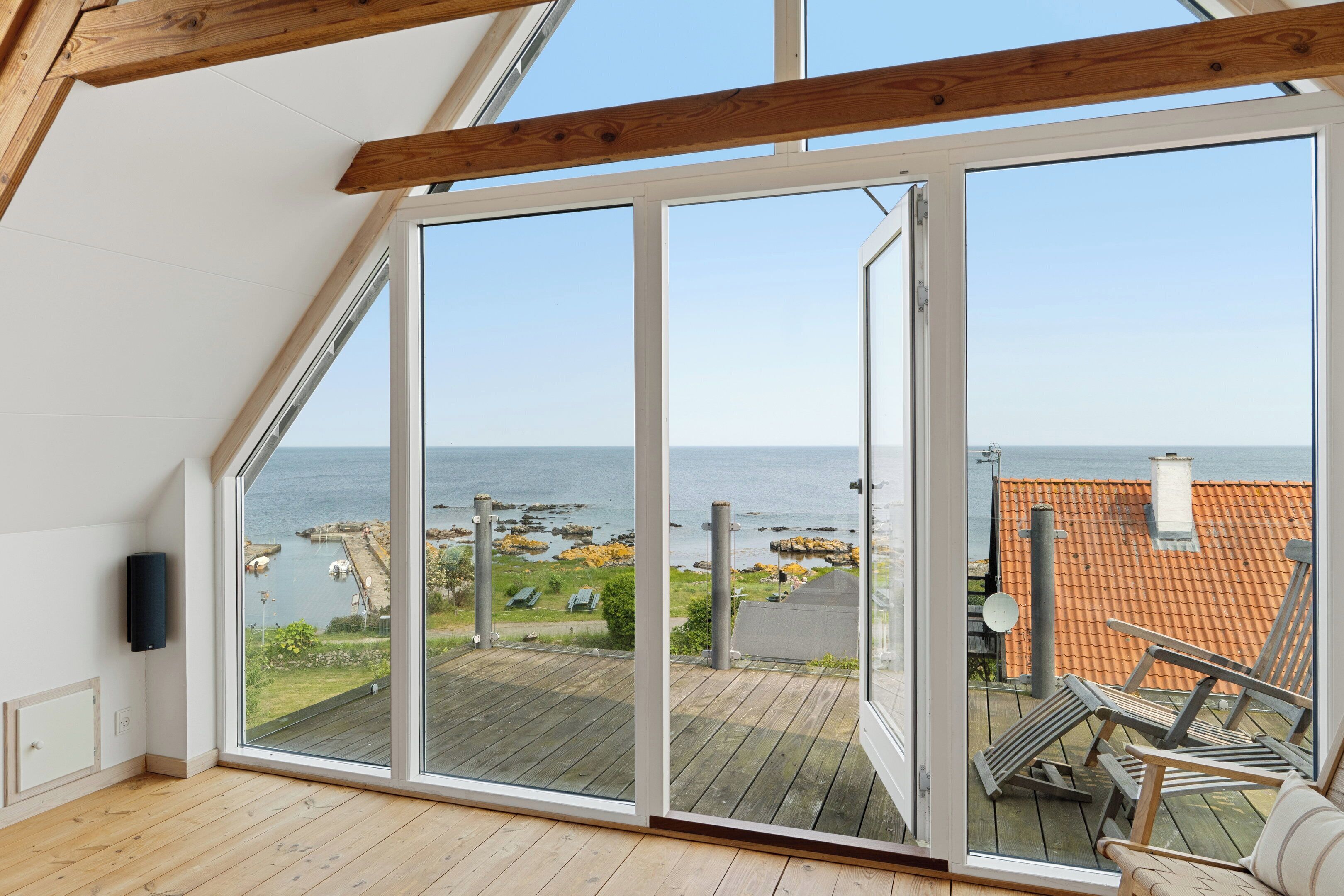 Una stanza con un'ampia porta scorrevole in vetro che si apre su un balcone con vista sul mare e un molo.