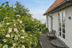 A house with a garden, a bench, and a view of the sea.